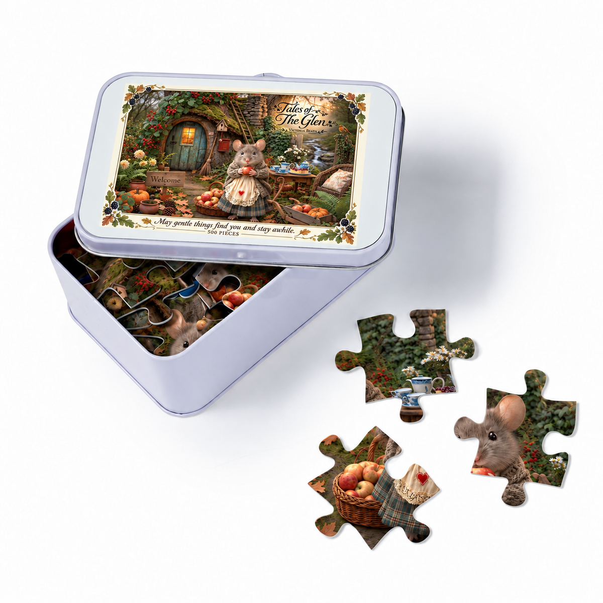 A completed jigsaw puzzle in a square metal tin with the lid propped open, alongside several loose puzzle pieces on a white background. The puzzle artwork shows a whimsical mouse in a glowing cottage by a stream